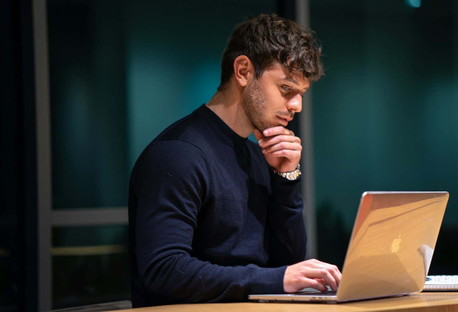 Professional thinking at laptop — quiet exhaustion in achievement